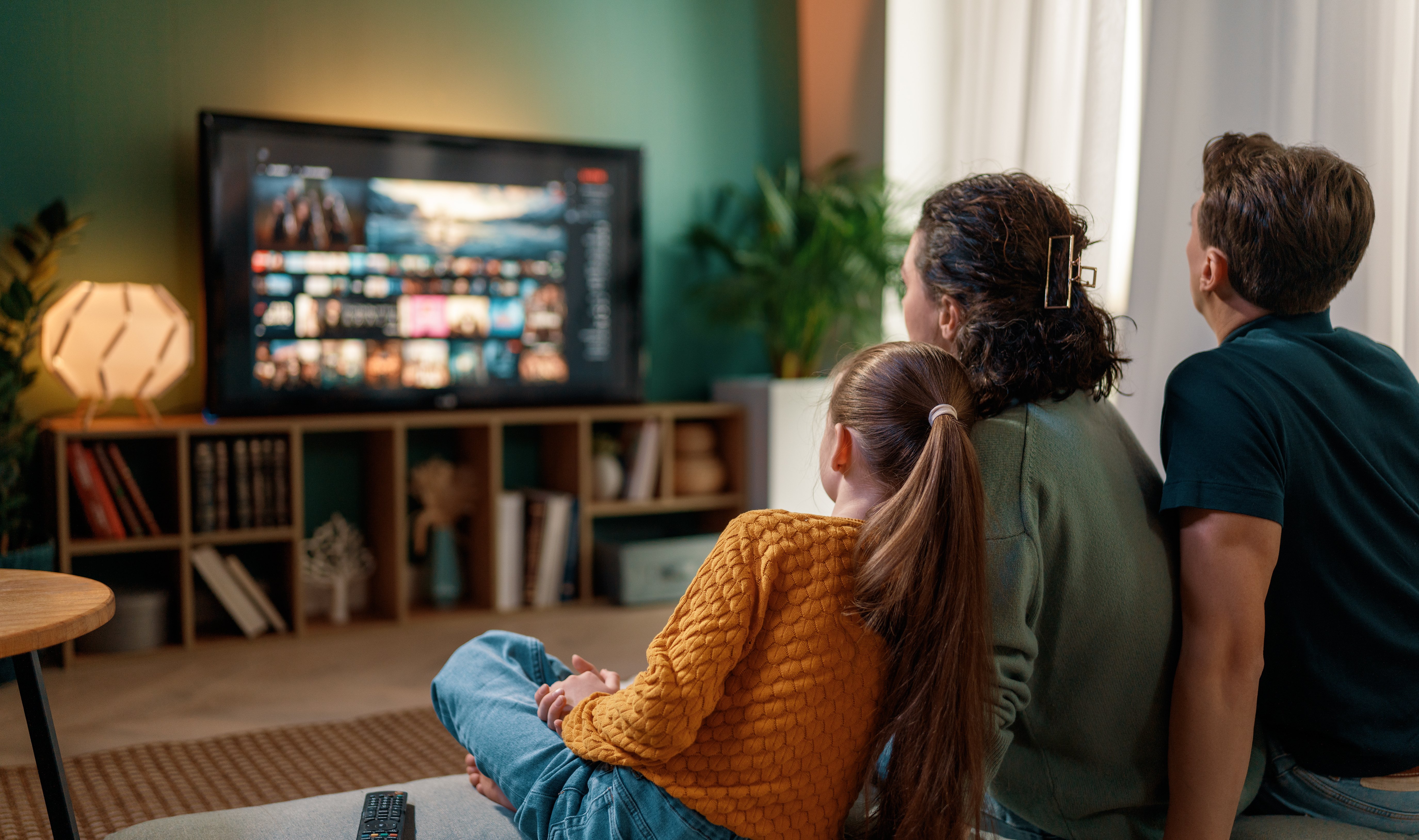 Family watching streaming CTV while being on mobile social media and searching products from ads